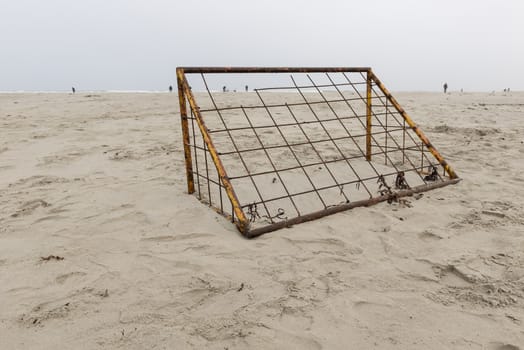 Rusted soccer goal on a beach with fishermen at sea on the island of Terschelling in Netherlands
