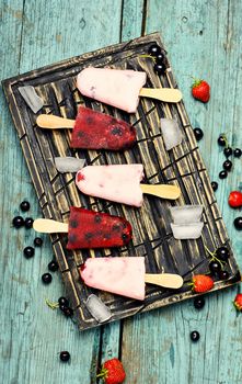 Berry ice cream on stick posted on stylish cutting board with berries and ice
