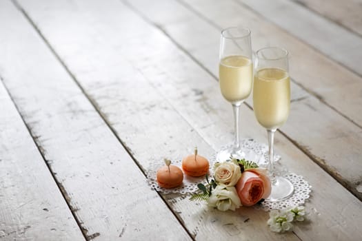 Two glasses with champagne, boutonniere with roses and cookies