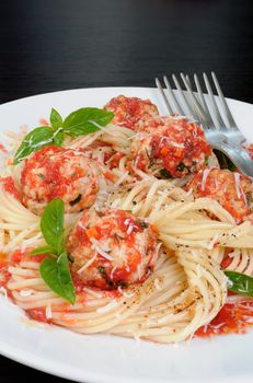 Pasta in tomato gravy with meatballs sprinkled Parmesan and basil
