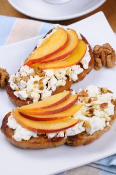 Sandwich of oat bread with ricotta and slices of peach, nuts, watering honey