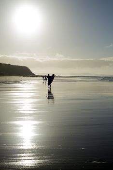 silhouette of surfer and people out for a walk as the sun sets in Ballybunion county Kerry Ireland