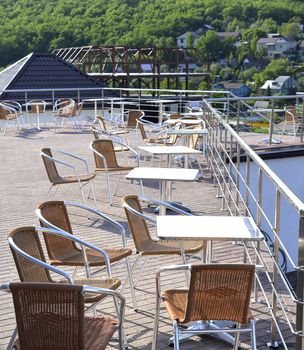 Wicker chairs with metal legs and racks are in an open cafe area