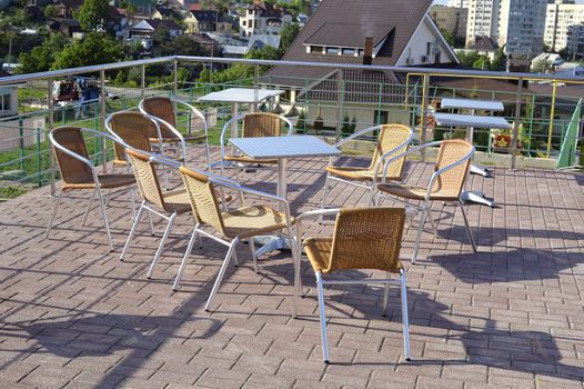 Wicker chairs with metal legs and racks are in an open cafe area