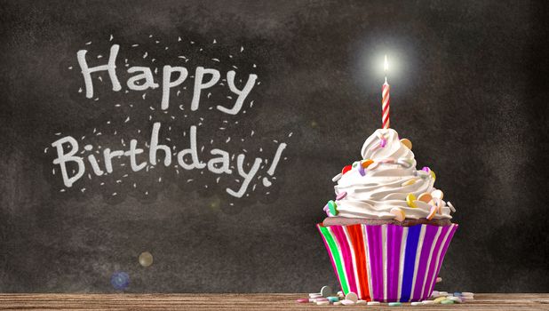 Cupcake with cream, candies and a candle on a wooden table with Happy Birthday written on a blackboard background. Empty free copy space available. 3D Rendering