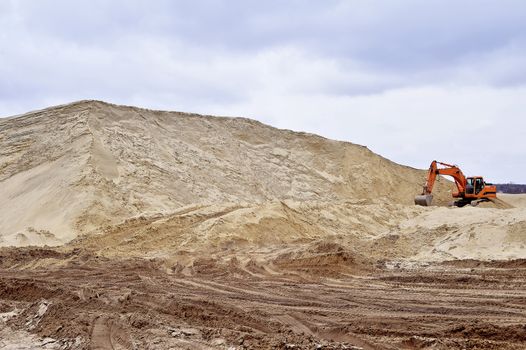 Working digger in a quarry produces sand.