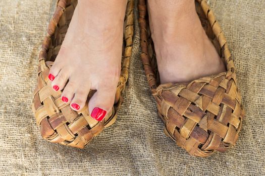 Feet girls with trendy pedicure in bast shoes stand on canvas.