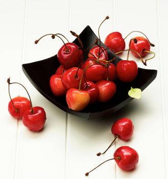 Ripe Sweet Maraschino Cherries in Black Wooden Plate closeup on White Plank  background