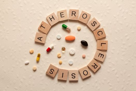 The word atherosclerosis formed with wooden letters between pills