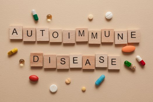 The word autoimmune disease formed with wooden letters and pills around