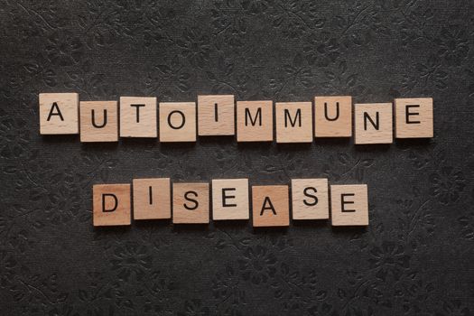 The word autoimmune disease formed with wooden letters on dark background