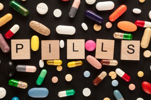 Word PILLS with wooden letters surrounded by colorful pills