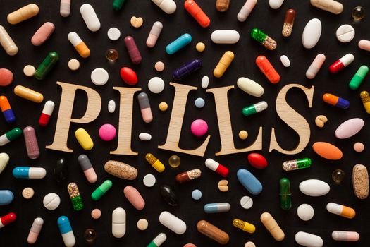 Word PILLS with wooden letters surrounded by colorful pills
