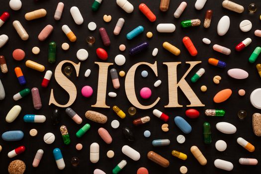 Word SICK with wooden letters surrounded by colorful pills