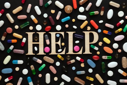 Word HELP with wooden letters surrounded by colorful pills