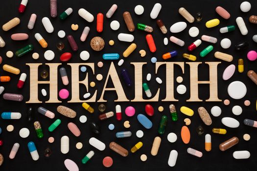 Word HEALTH with wooden letters surrounded by colorful pills