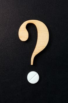 Question mark formed of wood and a pill