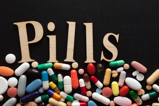 Word PILLS with wooden letters on colorful pills
