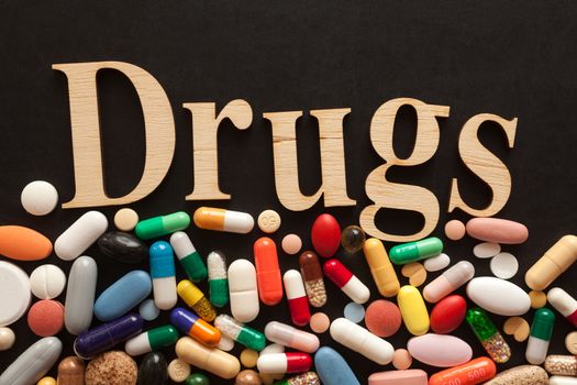 Word DRUGS with wooden letters on colorful pills