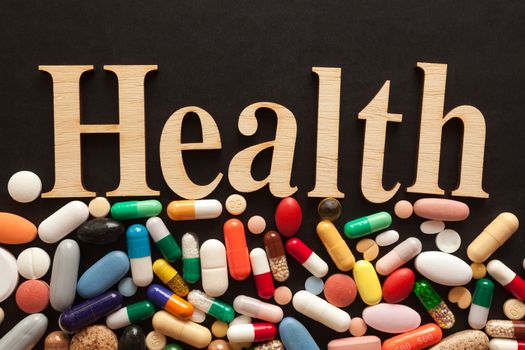 Word HEALTH with wooden letters on colorful pills