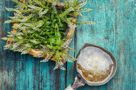 Tub with flowering medicinal mint on wooden background and pitcher of water