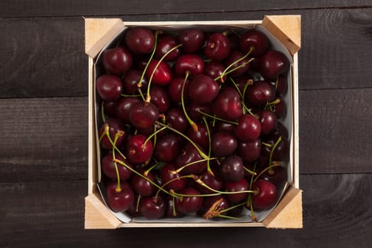 Cherries in a wooden box on wooden background