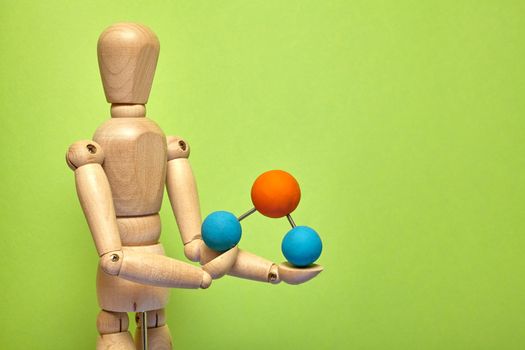 Wooden puppet with molecule on green background