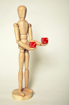 Wooden puppet holds dice on white background