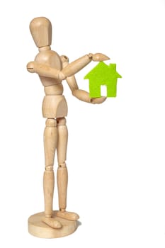 Wooden puppet holds small green house on white background