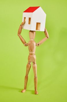 Dummy carrying small house on green background