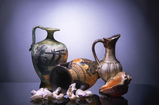 Antique amphora and jug,  big shell Rapana and scattered small seashells broken coastal waves
