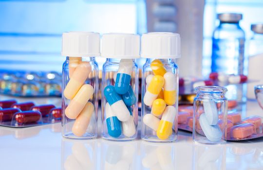 Colorful medical capsules in bottle, on white background.