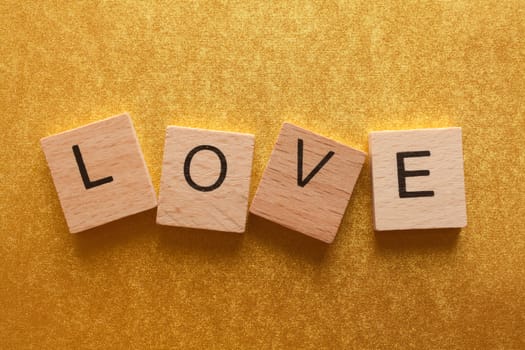 Wooden letters spelling LOVE on yellow background