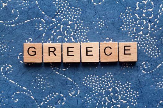 Wooden letters spelling GREECE on blue background