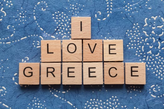 Wooden letters spelling I LOVE GREECE on blue background