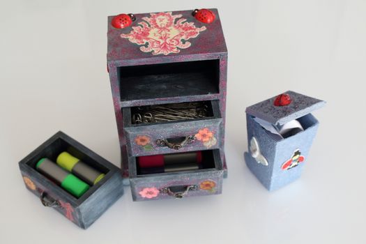 A handmade mini chest of three drawers decoupaged with floral vintage paper, handmade objects decorated using different techniques of decoupage