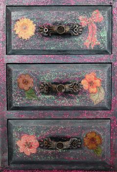 A handmade mini chest of three drawers decoupaged with floral vintage paper, handmade objects decorated using different techniques of decoupage