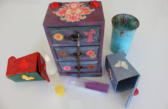 A handmade mini chest of three drawers decoupaged with floral vintage paper, handmade objects decorated using different techniques of decoupage