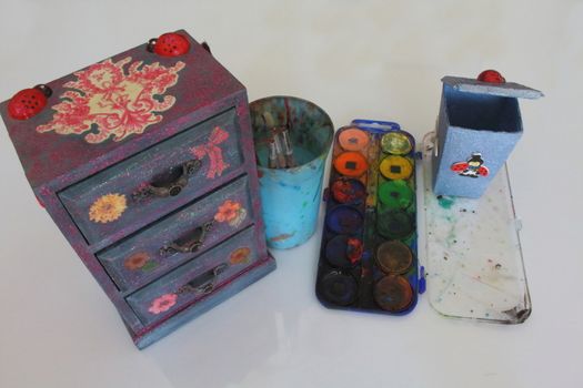 A handmade mini chest of three drawers decoupaged with floral vintage paper, handmade objects decorated using different techniques of decoupage