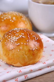 Buns with sesame seeds in a basket on table
