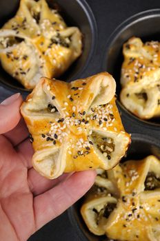 bun puff pastry with spinach and ricotta in a hand on a background of trays  baking