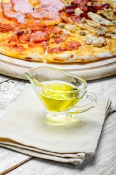 Gravy boat with olive oil on linen napkin to the pizza