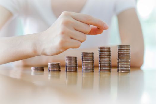 woman put coins to stack of coins