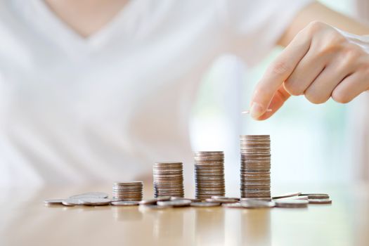 woman put coins to stack of coins