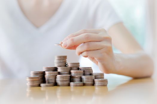 Close-up Of Businesswoman Putting Coin To Rising Stack Of Coins