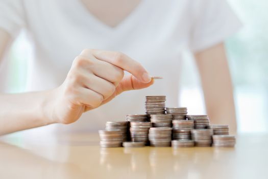 Close-up Of Businesswoman Putting Coin To Rising Stack Of Coins