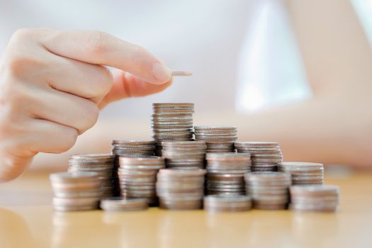 Hand put coins to stack of coins on white background