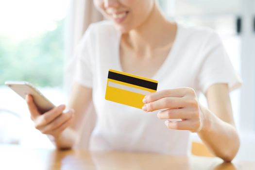 Happy woman shopping online with a credit card and a phone 