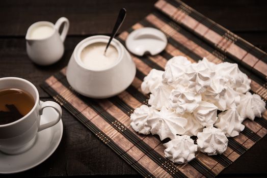 bizet on a brown wooden table with a cup of tea, sugar and milk