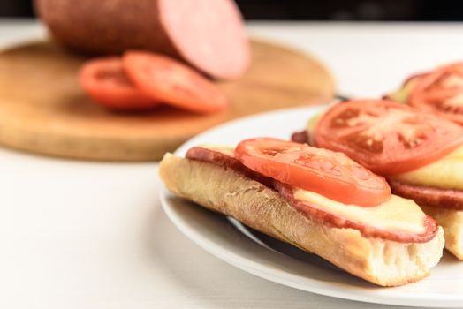 hot sandwiches with melted cheese sausage, salami and tomatoes